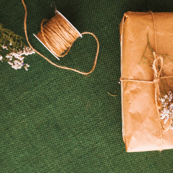 Rustic wedding invitations with a jute ribbon on a wooden table.