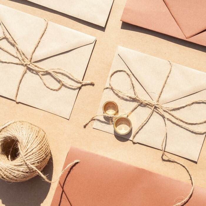 Personalized envelopes in terracotta and green colors for rustic wedding invitations.